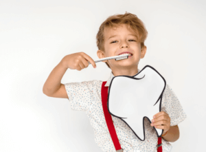 young patient brushing his teeth after dental bonding treatment while holding a big tooth illustration